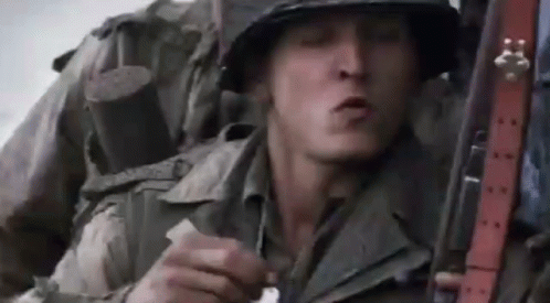 A Close Up Of A Soldier In A Helmet Holding A Gun And Smoking A Cigarette . GIF