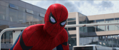 A Close Up Of A Spider Man In Front Of A Large Building GIF