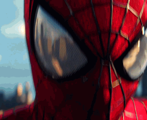 A Close Up Of A Spider Man 'S Eyes With A City In The Background GIF