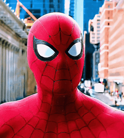 A Close Up Of A Spider Man 'S Face In Front Of A City GIF
