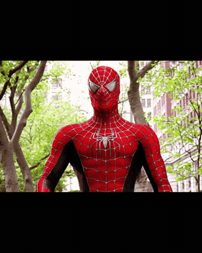 A Close Up Of A Spider Man Standing In Front Of A Building GIF