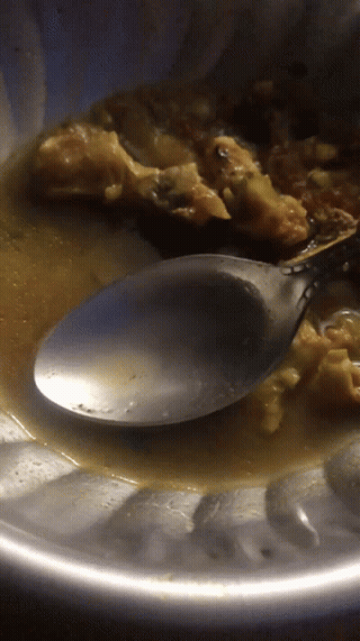 A Close Up Of A Spoon In A Bowl Of Sauce GIF