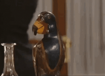 A Close Up Of A Statue Of A Parrot With A Yellow Beak On A Table . GIF