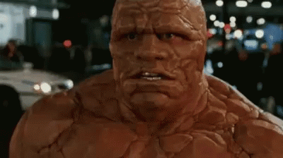 A Close Up Of A Superhero 'S Face With A Car In The Background GIF