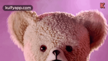 A Close Up Of A Teddy Bear 'S Face On A Pink Background GIF