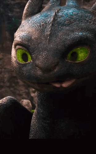 A Close Up Of A Toothless Dragon With Bright Green Eyes GIF