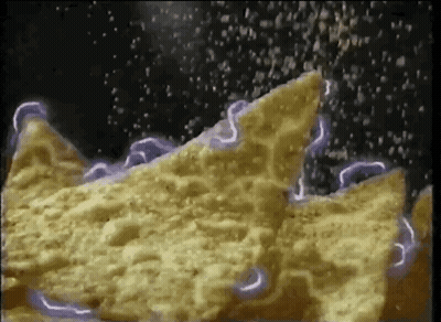 A Close Up Of A Tortilla Chip Being Sprinkled With Salt GIF