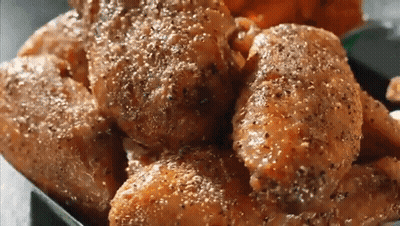 A Close Up Of A Tray Of Chicken Wings With Pepper On Them GIF