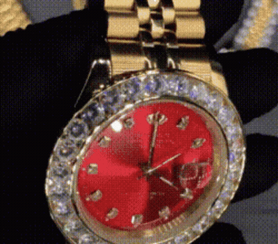 A Close Up Of A Watch With A Red Face And Diamonds GIF