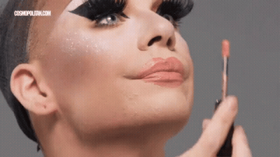 A Close Up Of A Woman Applying Lip Gloss With A Cosmopolitan.com Logo In The Corner GIF