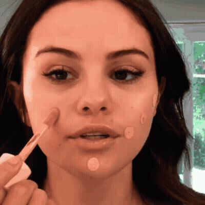 A Close Up Of A Woman Applying Makeup To Her Face GIF