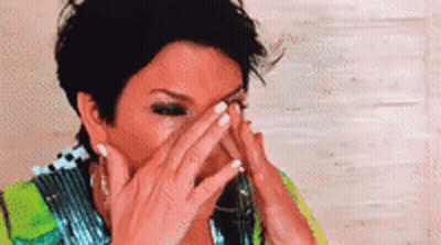 A Close Up Of A Woman Covering Her Face With Her Hands . GIF