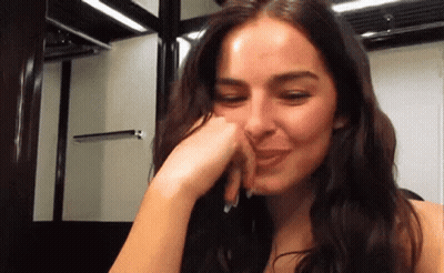 A Close Up Of A Woman Covering Her Mouth With Her Hand GIF