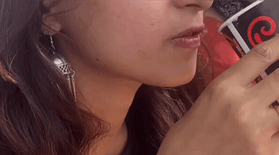 A Close Up Of A Woman Drinking From A Cup That Says Coca Cola On It GIF