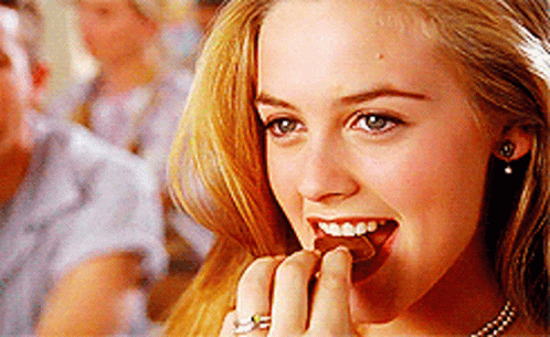 A Close Up Of A Woman Eating A Piece Of Chocolate GIF