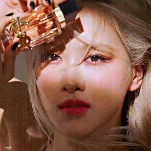 A Close Up Of A Woman Holding A Bottle Of Perfume On Her Forehead . GIF