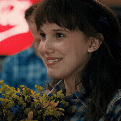 A Close Up Of A Woman Holding A Bouquet Of Flowers And Smiling GIF