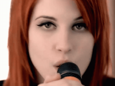 A Close Up Of A Woman Holding A Microphone In Her Mouth . GIF