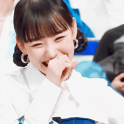 A Close Up Of A Woman Laughing With Her Hand To Her Mouth . GIF