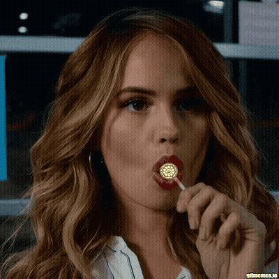 A Close Up Of A Woman Licking A Lollipop With Gifmemes.io In The Corner GIF