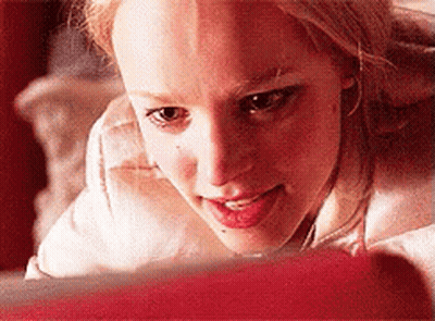 A Close Up Of A Woman Looking At A Red Object GIF
