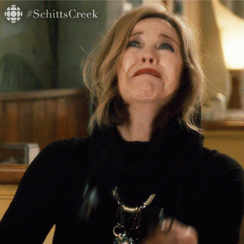 A Close Up Of A Woman Making A Face With #Schittscreek Written On The Bottom GIF