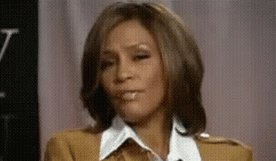 A Close Up Of A Woman Making A Funny Face While Sitting In Front Of A Pink Curtain . GIF