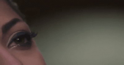 A Close Up Of A Woman 'S Eye With Long Eyelashes And A Green Background . GIF