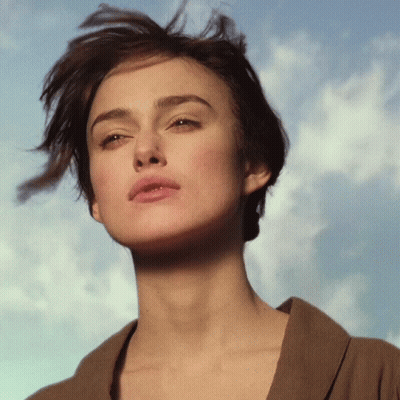 A Close Up Of A Woman 'S Face Against A Blue Sky With Clouds GIF