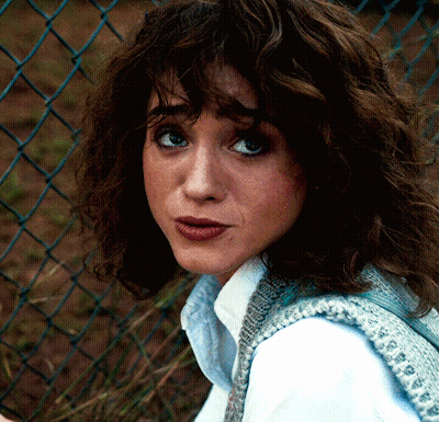 A Close Up Of A Woman 'S Face Against A Chain Link Fence GIF