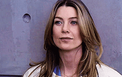 A Close Up Of A Woman 'S Face Against A Gray Wall . GIF