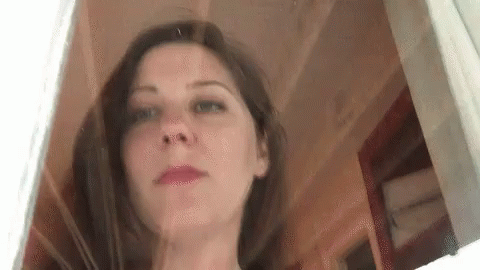 A Close Up Of A Woman 'S Face Behind A Glass Door . GIF