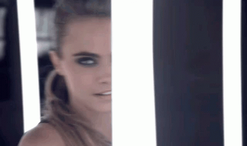 A Close Up Of A Woman 'S Face Behind A Striped Wall With Lights . GIF