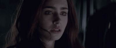 A Close Up Of A Woman 'S Face In A Dark Room Looking At The Camera . GIF