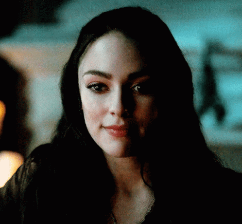 A Close Up Of A Woman 'S Face In A Dark Room Looking At The Camera . GIF