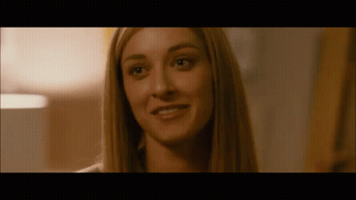 A Close Up Of A Woman 'S Face In A Dark Room Smiling . GIF