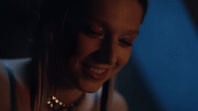 A Close Up Of A Woman 'S Face In A Dark Room With A Blue Background GIF