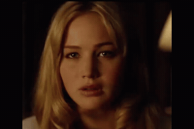 A Close Up Of A Woman 'S Face In A Dark Room With A Light Behind Her . GIF