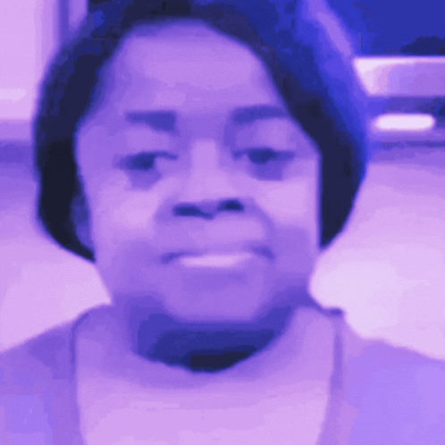 A Close Up Of A Woman 'S Face In A Purple Light GIF