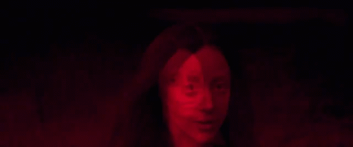 A Close Up Of A Woman 'S Face In A Red Light GIF