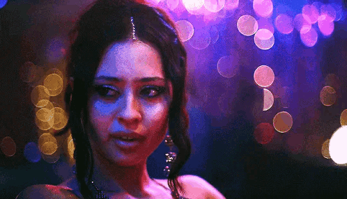 A Close Up Of A Woman 'S Face In Front Of A Blurry Background Of Lights . GIF