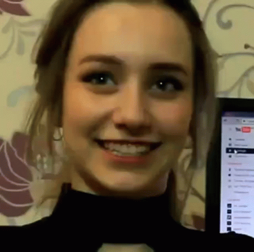 A Close Up Of A Woman 'S Face Smiling In Front Of A Laptop Computer . GIF