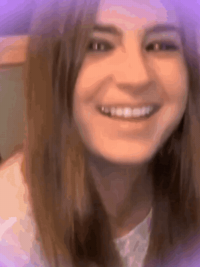A Close Up Of A Woman 'S Face Smiling With A Purple Background . GIF
