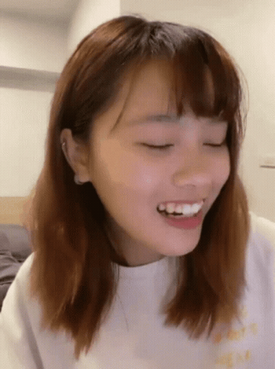 A Close Up Of A Woman 'S Face Smiling With Her Eyes Closed . GIF