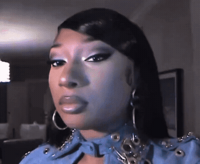 A Close Up Of A Woman 'S Face Wearing A Blue Jacket And Earrings . GIF