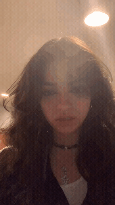 A Close Up Of A Woman 'S Face Wearing A Choker Necklace And Earrings GIF