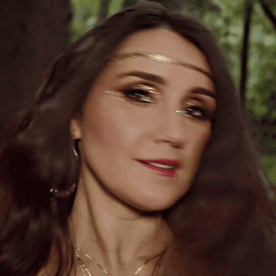 A Close Up Of A Woman 'S Face Wearing A Gold Headband GIF