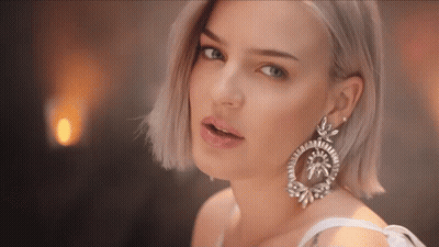 A Close Up Of A Woman 'S Face Wearing A Pair Of Earrings GIF
