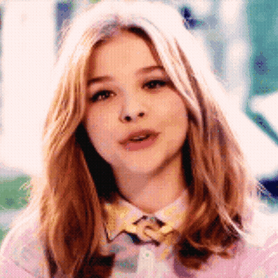 A Close Up Of A Woman 'S Face Wearing A Pink Shirt And A Yellow Bow Tie . GIF