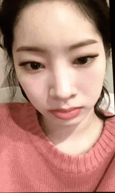 A Close Up Of A Woman 'S Face Wearing A Pink Sweater And Red Lipstick . GIF